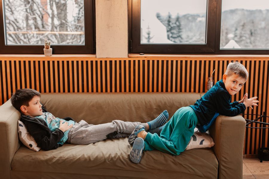 Deca se odmaraju na sofi pored prozora sa pogledom na zimski Kopaonik