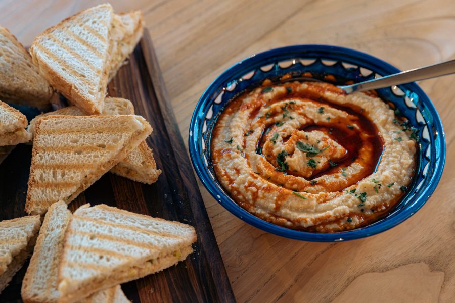 Humus sa tostiranim sendvičima na drvenoj dasci