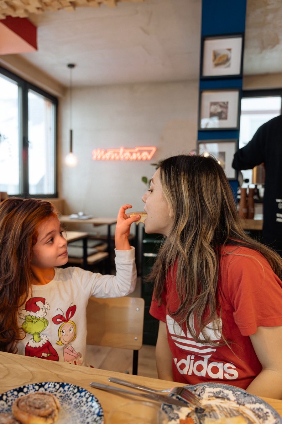 Mama i ćerka za doručkom ispod neonskog natpisa
