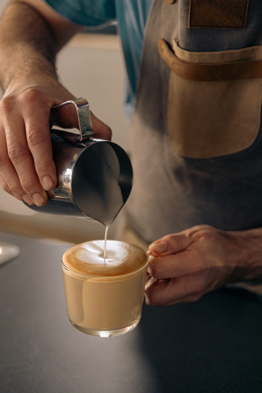 Barista sipa mleko u kafu za latte art